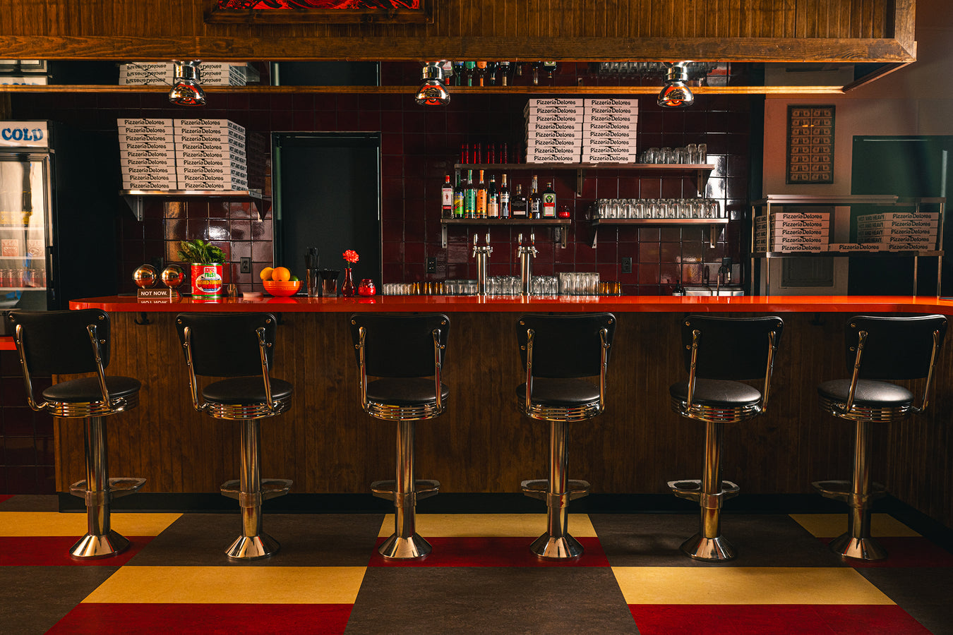The bar at Pizzeria Delores with red counter and chrome stools