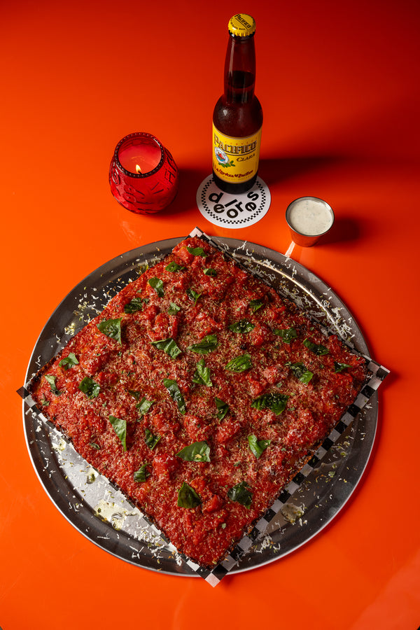 Whole Sicilian pie with basil next to a cold beer